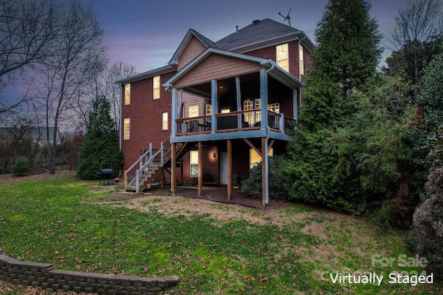 back house at dusk featuring a deck and a lawn