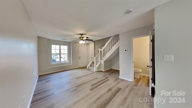 unfurnished living room featuring a textured ceiling, light hardwood / wood-style floors, and ceiling fan