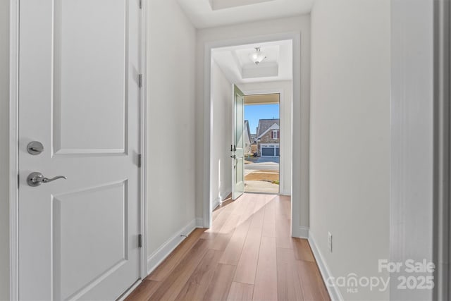 corridor featuring a tray ceiling and light hardwood / wood-style flooring