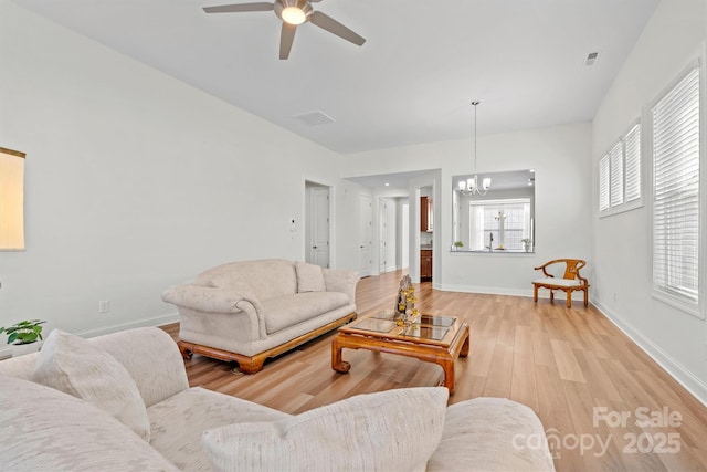 living room featuring ceiling fan with notable chandelier and light hardwood / wood-style floors