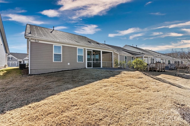 rear view of property with central air condition unit and a yard