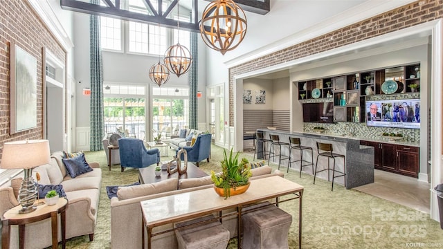 living room featuring brick wall, a high ceiling, and an inviting chandelier