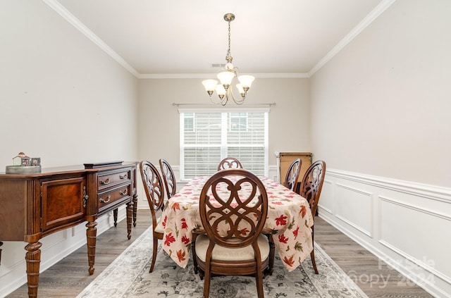 dining area featuring hardwood / wood-style floors, a notable chandelier, and ornamental molding