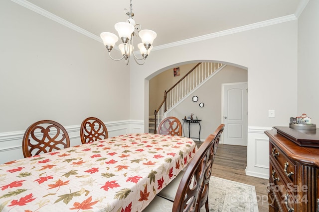 dining room with hardwood / wood-style floors, a notable chandelier, and crown molding