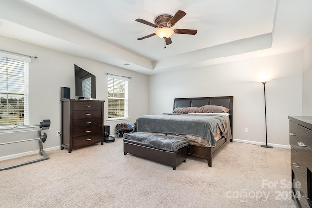 carpeted bedroom featuring a raised ceiling and ceiling fan