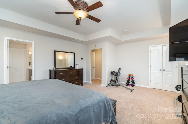 carpeted bedroom with a closet, a tray ceiling, and ceiling fan