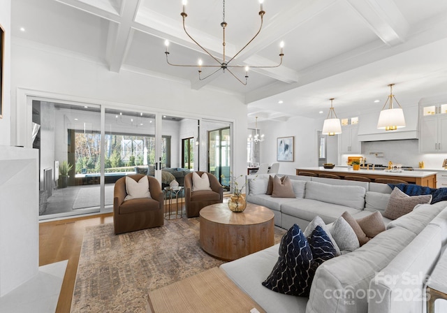 living room with an inviting chandelier, beam ceiling, coffered ceiling, and light wood-type flooring