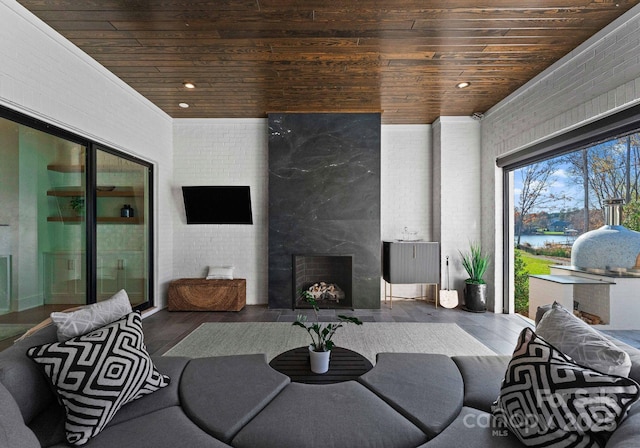 living room with a premium fireplace, brick wall, dark hardwood / wood-style floors, and wooden ceiling