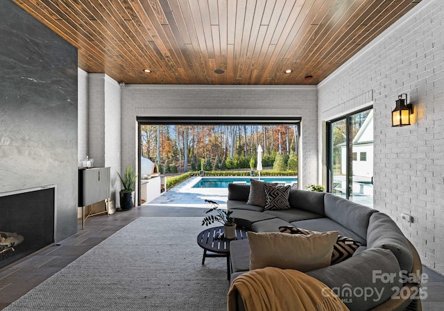 living room with brick wall, a fireplace, and wood ceiling