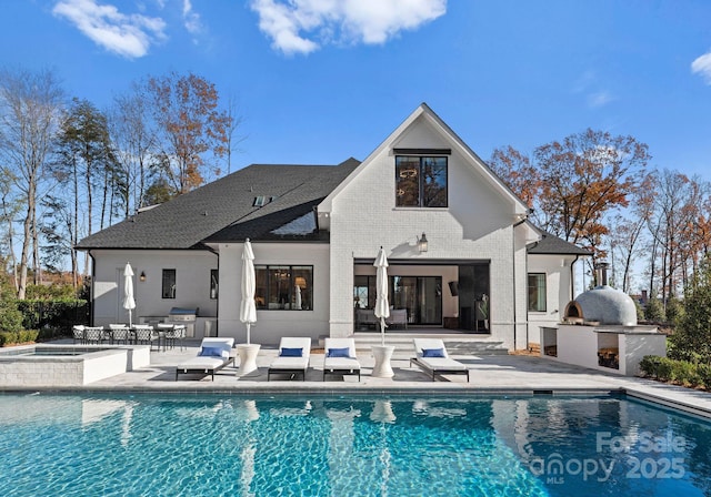 rear view of house featuring area for grilling, a patio, and a swimming pool with hot tub