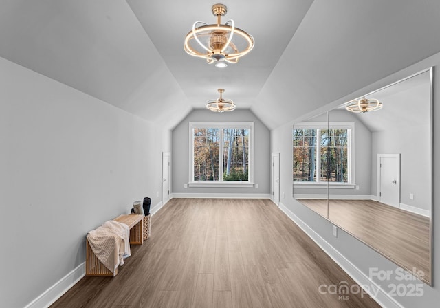 bonus room featuring lofted ceiling, wood-type flooring, and a chandelier