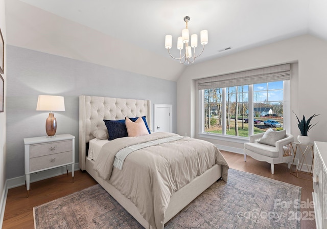 bedroom with dark hardwood / wood-style flooring, lofted ceiling, and an inviting chandelier