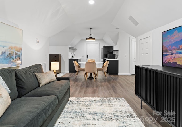 living room featuring wood-type flooring, lofted ceiling, and sink