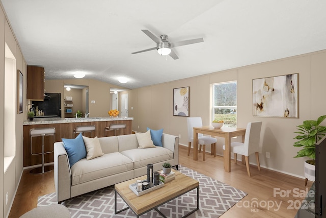 living room featuring hardwood / wood-style flooring, ceiling fan, and lofted ceiling