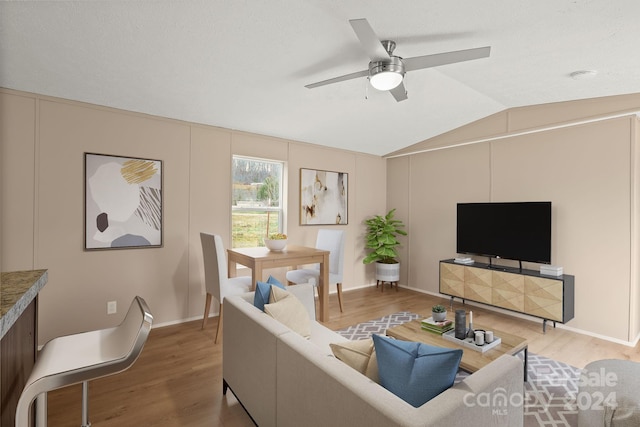 living room with hardwood / wood-style flooring, ceiling fan, and lofted ceiling