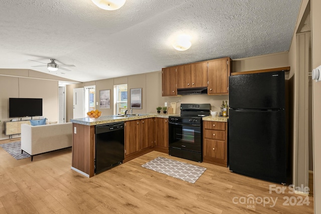 kitchen featuring kitchen peninsula, light hardwood / wood-style flooring, black appliances, and extractor fan