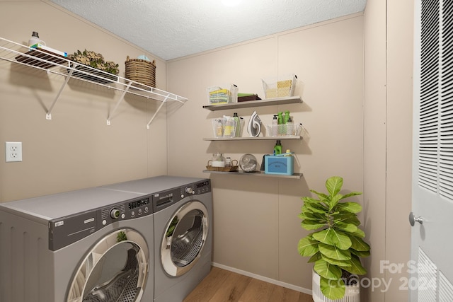 laundry area featuring separate washer and dryer, light hardwood / wood-style floors, and a textured ceiling