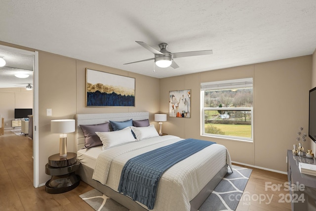 bedroom with ceiling fan, a textured ceiling, and light wood-type flooring