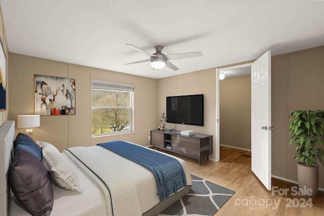 bedroom with ceiling fan, light hardwood / wood-style floors, and a textured ceiling