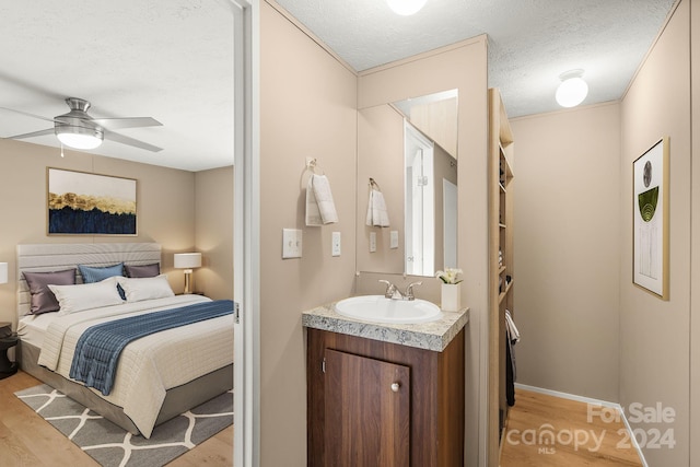 bedroom featuring ceiling fan, sink, light hardwood / wood-style floors, and a textured ceiling