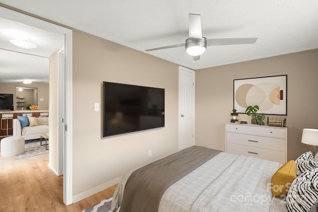 bedroom featuring ceiling fan, a textured ceiling, and light hardwood / wood-style flooring