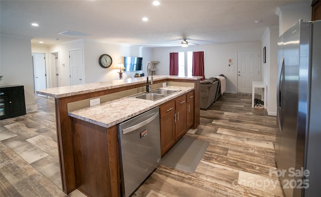 kitchen with ceiling fan, sink, an island with sink, wood-type flooring, and appliances with stainless steel finishes