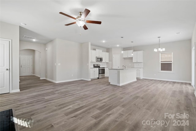 unfurnished living room featuring ceiling fan with notable chandelier, light wood-type flooring, and sink