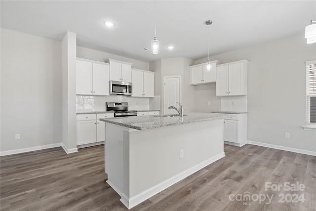 kitchen featuring white cabinets, sink, an island with sink, light stone counters, and stainless steel appliances