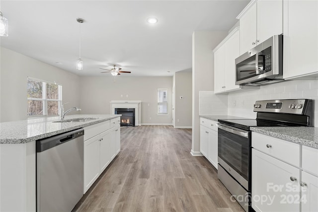 kitchen featuring hanging light fixtures, white cabinetry, sink, and stainless steel appliances