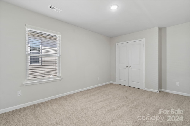 unfurnished bedroom with light carpet and a closet