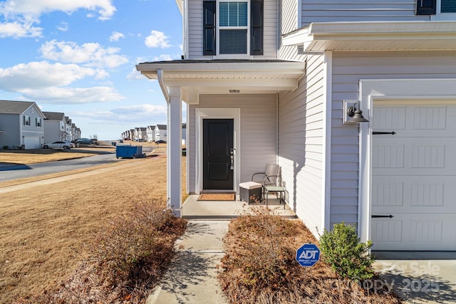 view of exterior entry featuring a yard and a garage