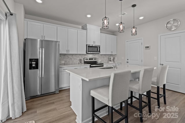 kitchen with white cabinets, sink, stainless steel appliances, and a kitchen island with sink