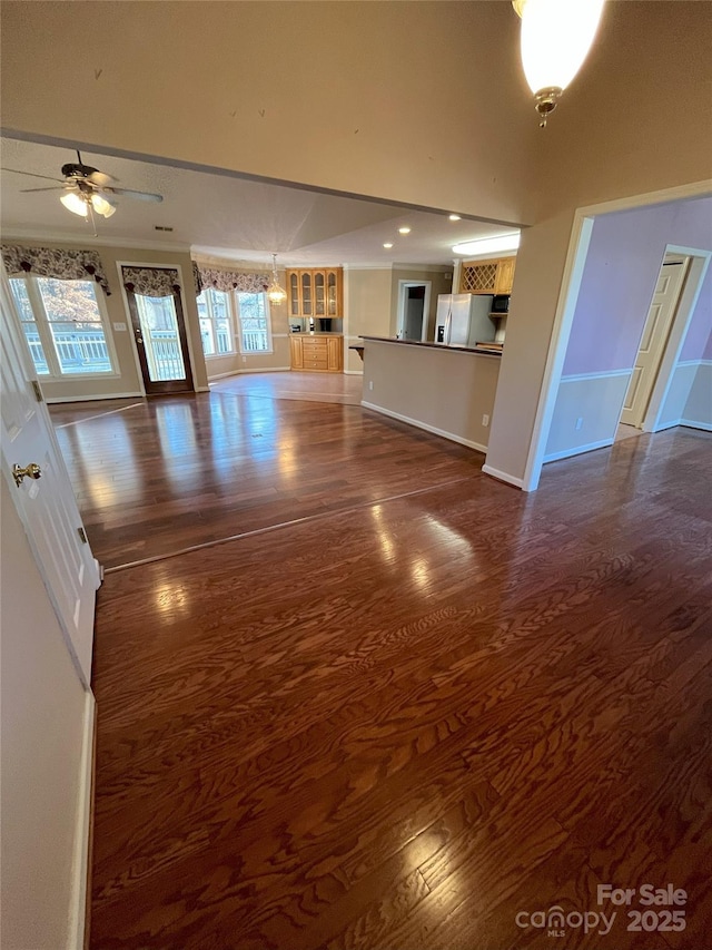 unfurnished living room with ceiling fan and dark wood-type flooring