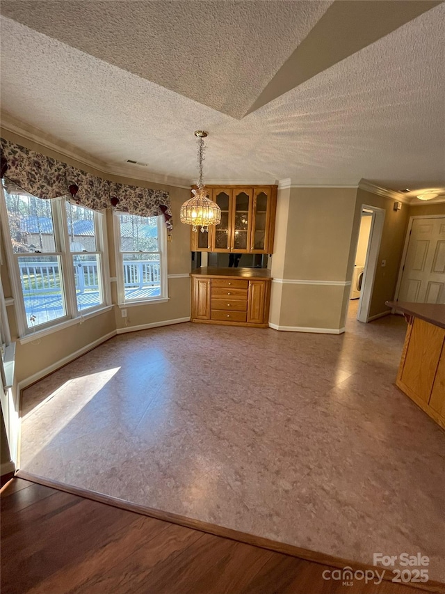 unfurnished dining area featuring a chandelier, lofted ceiling, and crown molding