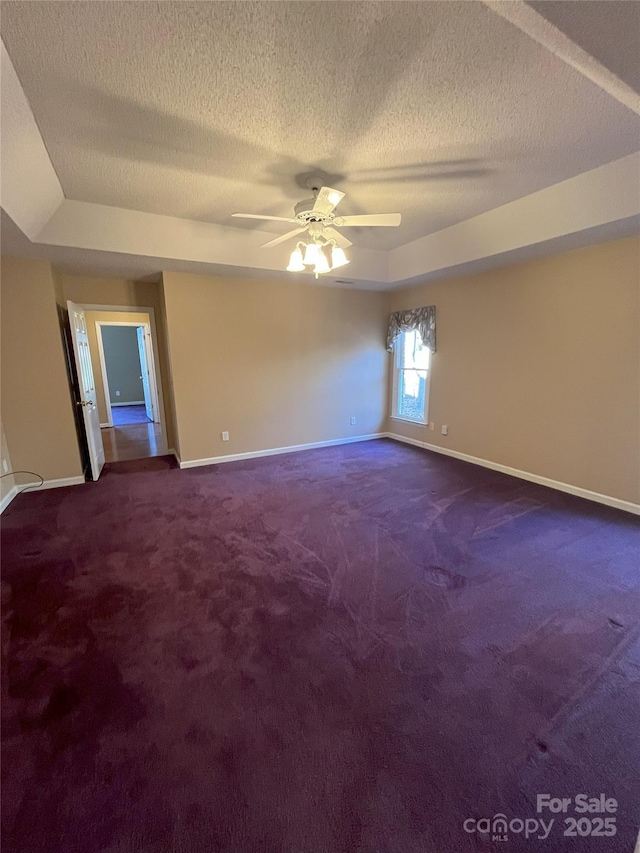 carpeted empty room with ceiling fan, a textured ceiling, and a tray ceiling