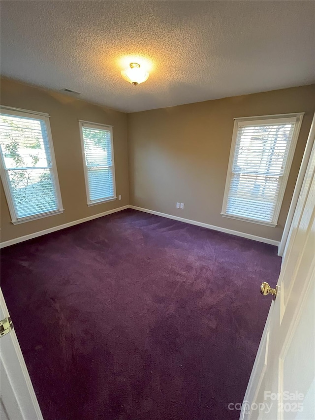 unfurnished room featuring dark carpet and a textured ceiling