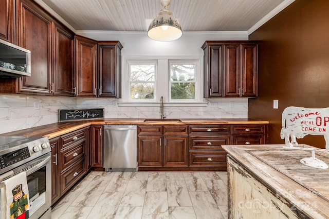 kitchen featuring wood counters, appliances with stainless steel finishes, crown molding, and sink