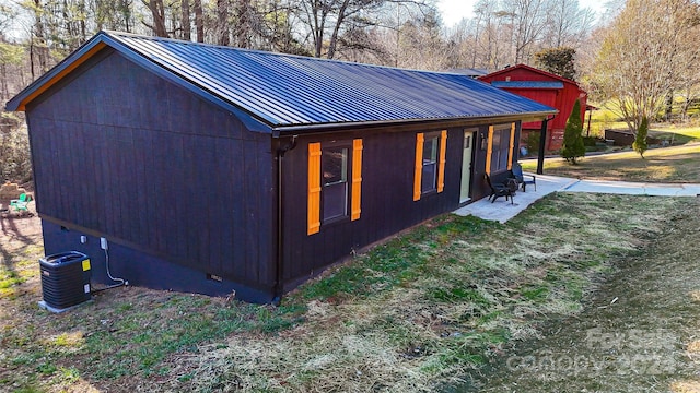 view of side of property featuring a patio, central AC unit, and a lawn