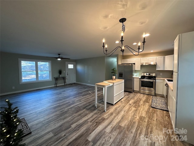 kitchen featuring hanging light fixtures, hardwood / wood-style floors, white cabinets, ceiling fan with notable chandelier, and appliances with stainless steel finishes