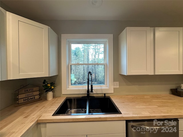 kitchen featuring stainless steel dishwasher, white cabinetry, and sink