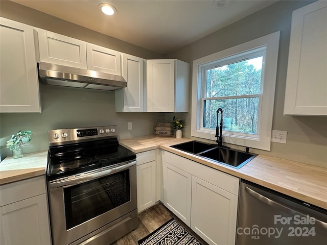 kitchen featuring hardwood / wood-style floors, white cabinets, sink, appliances with stainless steel finishes, and extractor fan