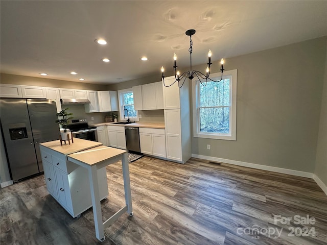 kitchen featuring white cabinetry, sink, a center island, pendant lighting, and appliances with stainless steel finishes