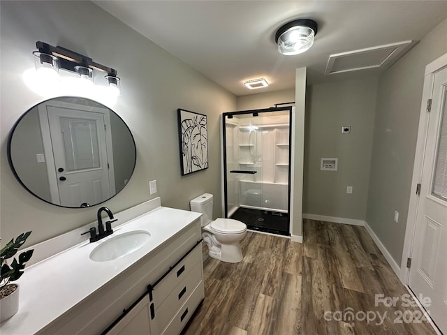 bathroom with hardwood / wood-style flooring, vanity, an enclosed shower, and toilet