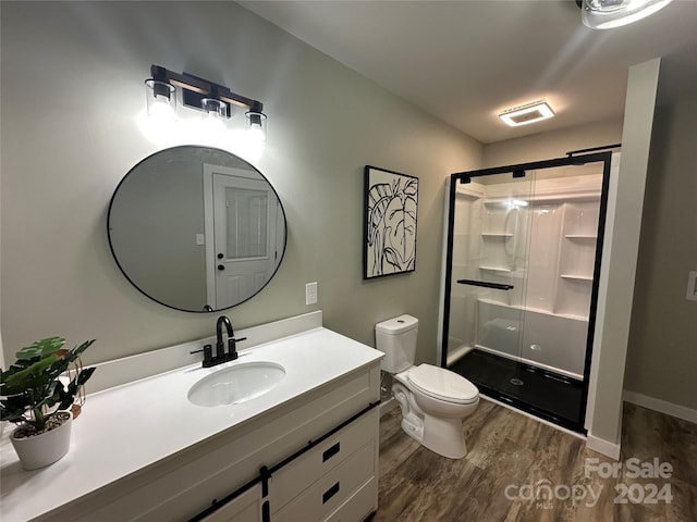 bathroom with hardwood / wood-style flooring, vanity, toilet, and walk in shower