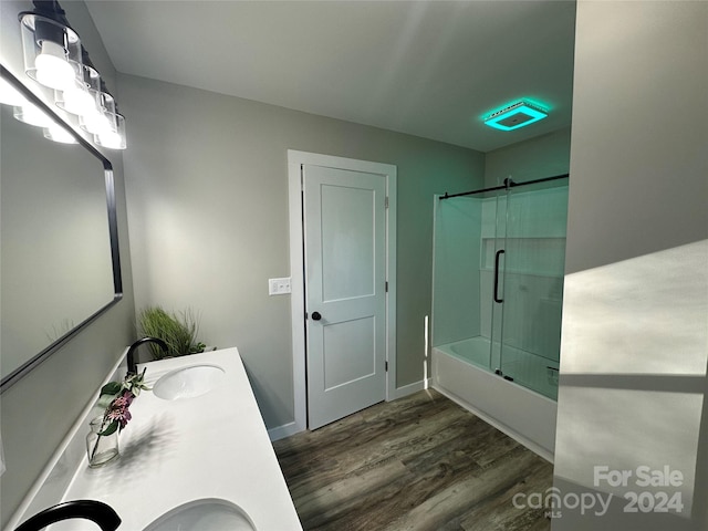 bathroom with wood-type flooring, vanity, and bath / shower combo with glass door