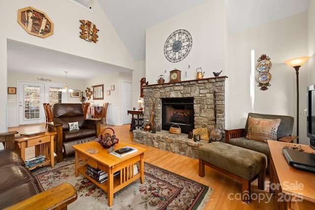 2959/2961 Bearwallow Mountain Rd, Hendersonville, NC 28792 - living room with light wood-type flooring, high vaulted ceiling, a stone fireplace, and a notable chandelier