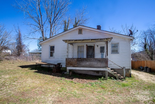 bungalow featuring a chimney, covered porch, a front yard, and fence