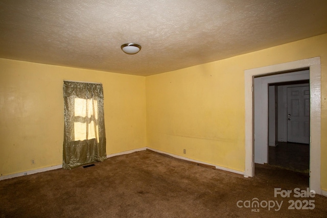 carpeted empty room featuring visible vents, a textured ceiling, and baseboards