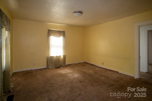 empty room with baseboards, visible vents, a textured ceiling, and carpet