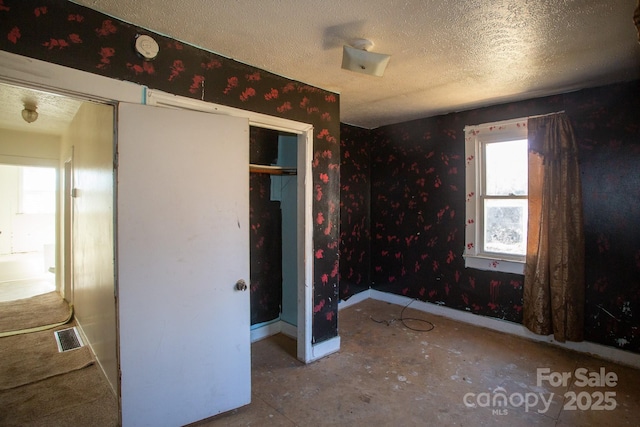 unfurnished bedroom with visible vents, a closet, and a textured ceiling